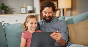 Mann mit Kind die auf einen Computer schauen Mann mit Kind die auf einen Computer schauen